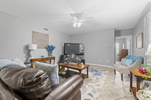 living room with ceiling fan and a textured ceiling