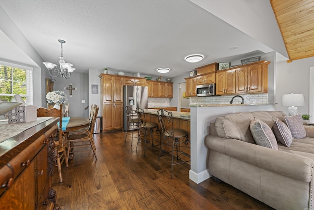 living room featuring dark hardwood / wood-style flooring, sink, vaulted ceiling, and a chandelier