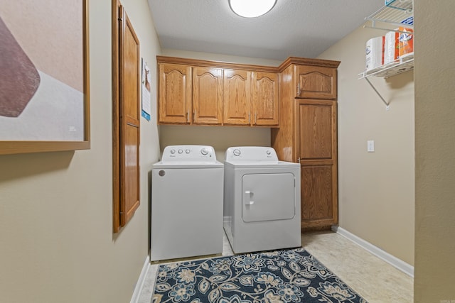 laundry room with a textured ceiling, cabinets, and washing machine and clothes dryer