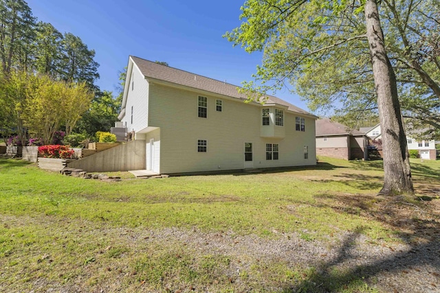 rear view of property featuring a garage and a lawn