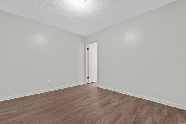 spare room featuring dark hardwood / wood-style flooring and a textured ceiling