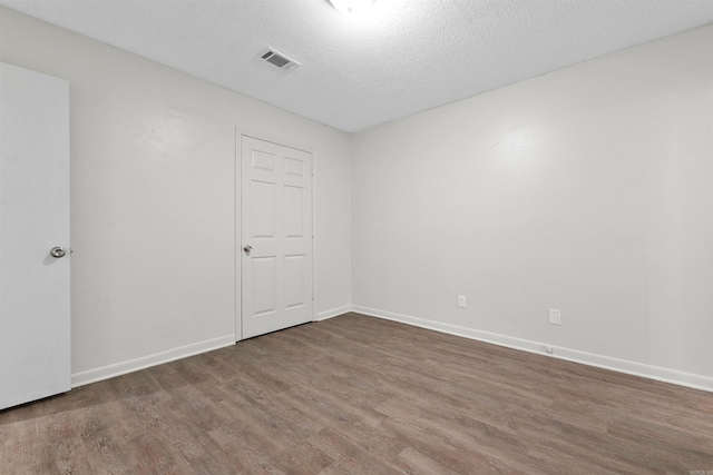 unfurnished room featuring dark wood-type flooring and a textured ceiling