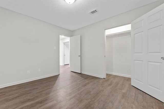 unfurnished bedroom featuring hardwood / wood-style floors, a closet, and a textured ceiling