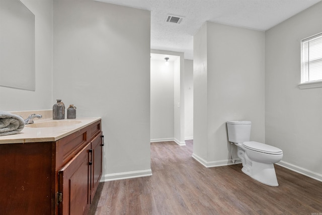 bathroom with vanity, wood-type flooring, a textured ceiling, and toilet