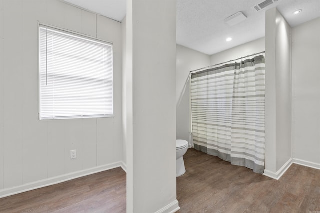 bathroom with hardwood / wood-style flooring, toilet, a textured ceiling, and a shower with curtain