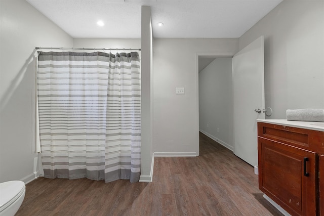 bathroom with wood-type flooring, toilet, vanity, and walk in shower