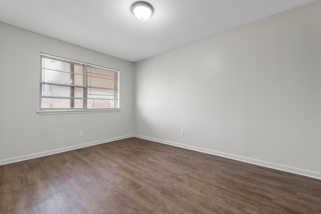 spare room with dark hardwood / wood-style floors and a textured ceiling