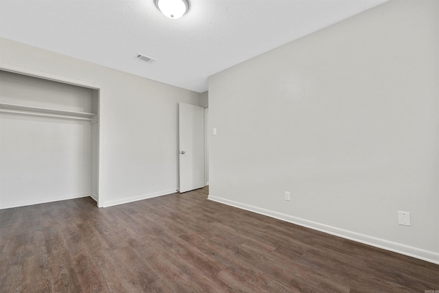 unfurnished bedroom with dark wood-type flooring, a closet, and a textured ceiling