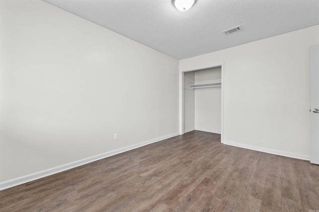 unfurnished bedroom with dark wood-type flooring, a closet, and a textured ceiling