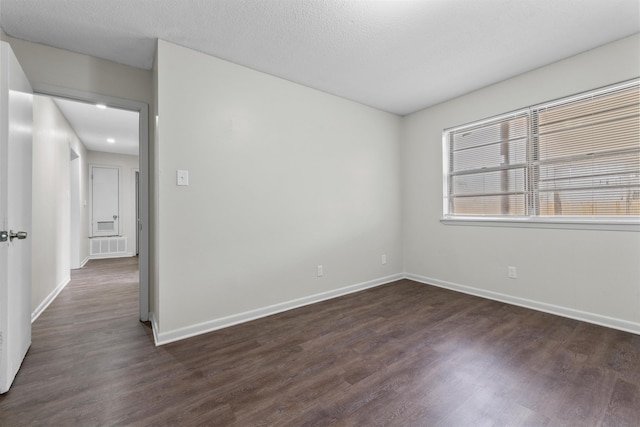 empty room featuring dark wood-type flooring and a textured ceiling