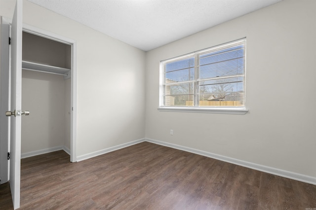 unfurnished bedroom with a closet, dark hardwood / wood-style floors, and a textured ceiling