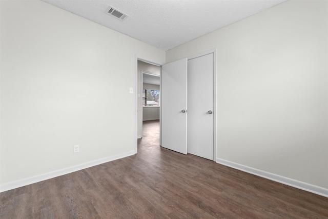 unfurnished bedroom with dark hardwood / wood-style floors and a textured ceiling