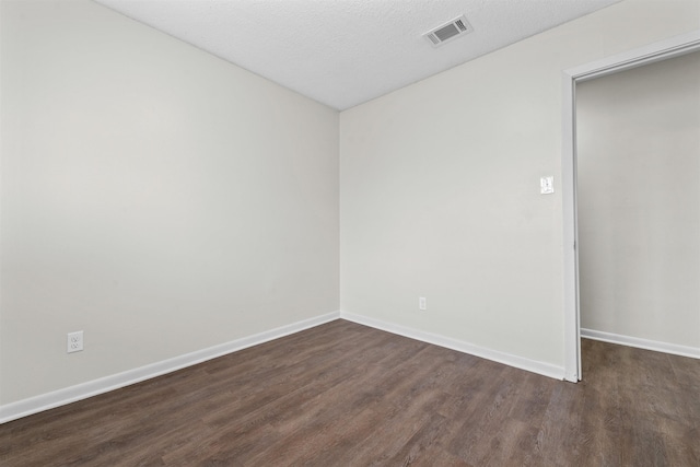 empty room with dark wood-type flooring and a textured ceiling