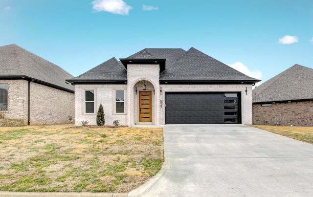 french country inspired facade featuring a garage and a front lawn