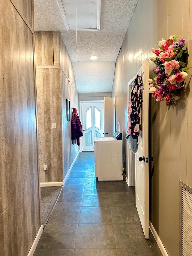 hallway with wooden walls and a textured ceiling