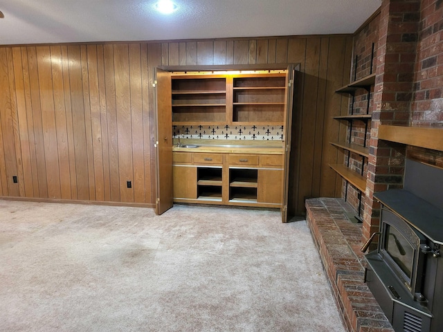 bar featuring light colored carpet, wood walls, and a wood stove