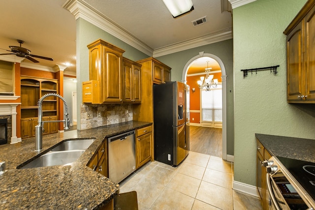 kitchen with light tile patterned flooring, sink, tasteful backsplash, stainless steel appliances, and ceiling fan with notable chandelier