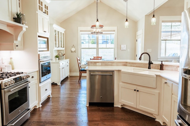 kitchen featuring appliances with stainless steel finishes, pendant lighting, sink, white cabinets, and dark wood-type flooring