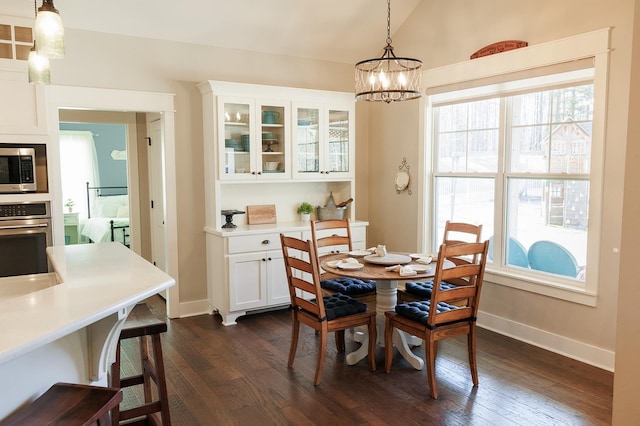 dining space featuring dark hardwood / wood-style floors, vaulted ceiling, and a notable chandelier