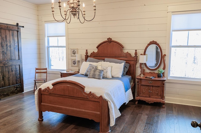 bedroom featuring dark wood-type flooring, a barn door, a chandelier, and wood walls