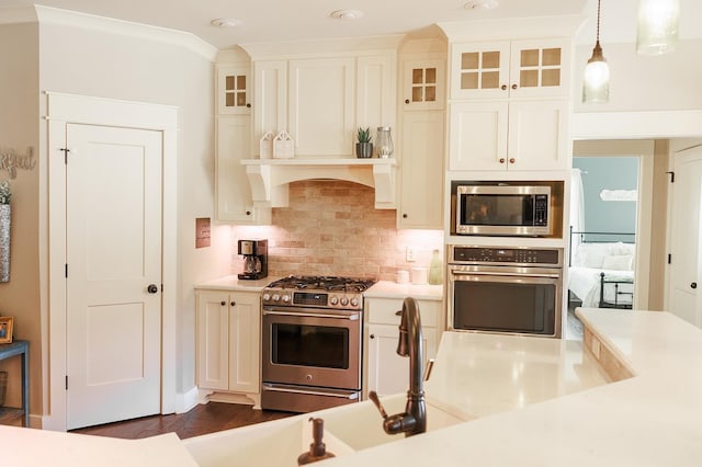 kitchen with dark wood-type flooring, white cabinetry, hanging light fixtures, stainless steel appliances, and decorative backsplash