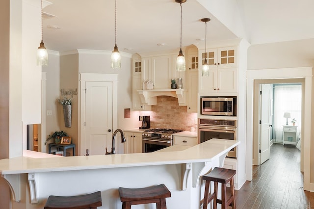 kitchen featuring appliances with stainless steel finishes, a breakfast bar, pendant lighting, and kitchen peninsula