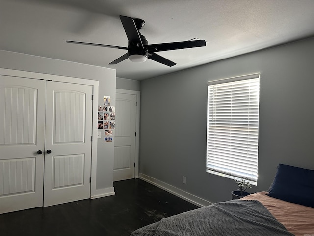 bedroom with dark wood-type flooring, ceiling fan, and a closet