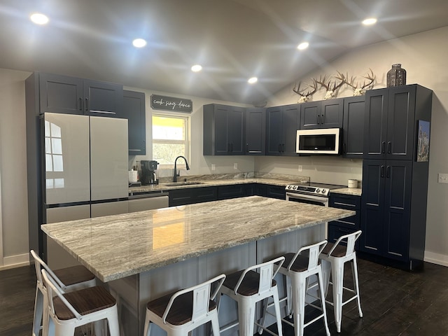 kitchen featuring sink, light stone counters, vaulted ceiling, a kitchen breakfast bar, and a kitchen island