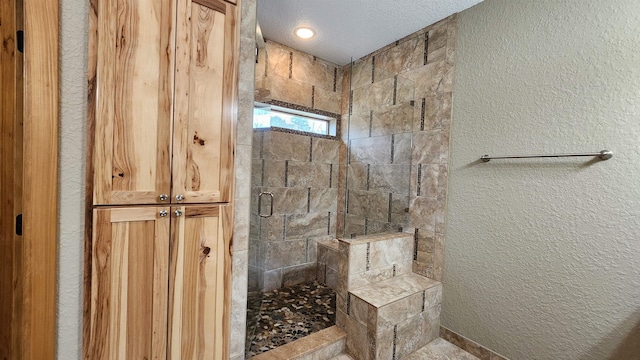 bathroom featuring a textured ceiling and a shower with shower door