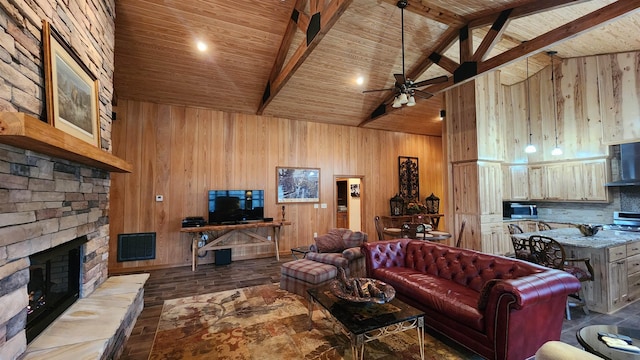 living room featuring beamed ceiling, a stone fireplace, light hardwood / wood-style floors, and wood walls