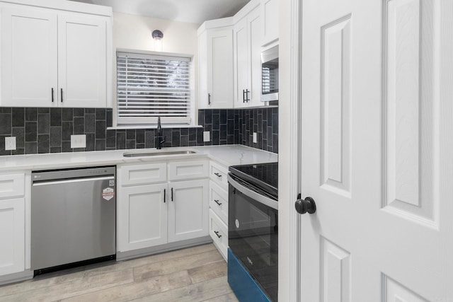 kitchen featuring sink, appliances with stainless steel finishes, light hardwood / wood-style floors, decorative backsplash, and white cabinets