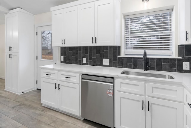 kitchen featuring tasteful backsplash, stainless steel dishwasher, sink, and white cabinets