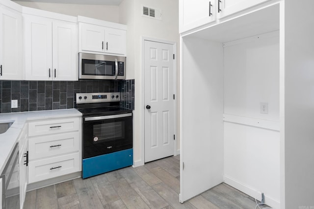 kitchen featuring white cabinetry, decorative backsplash, stainless steel appliances, and light hardwood / wood-style floors