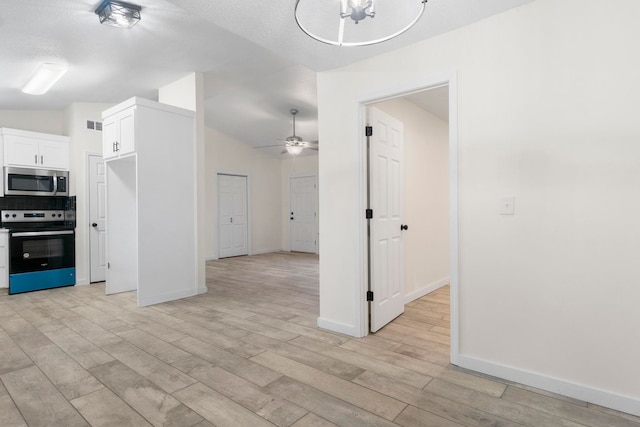 kitchen featuring white cabinetry, vaulted ceiling, light wood-type flooring, ceiling fan, and stainless steel appliances