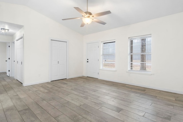 empty room with ceiling fan, light hardwood / wood-style floors, and vaulted ceiling