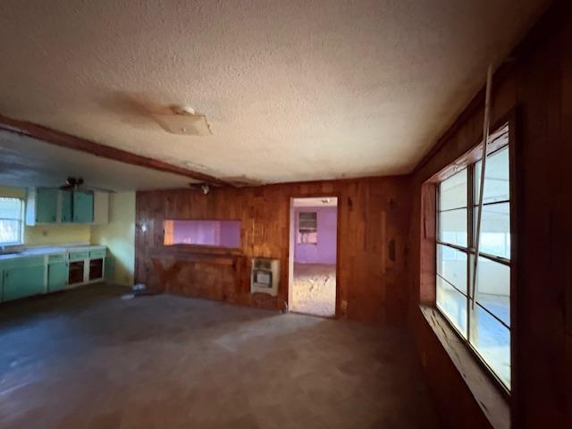 unfurnished living room with a textured ceiling and wooden walls