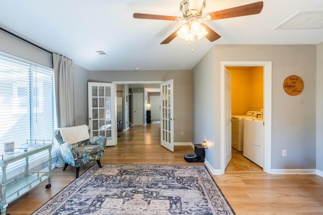 living area featuring ceiling fan, washer and dryer, light wood-type flooring, and french doors