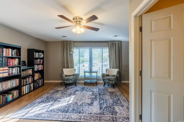 sitting room with hardwood / wood-style floors and ceiling fan