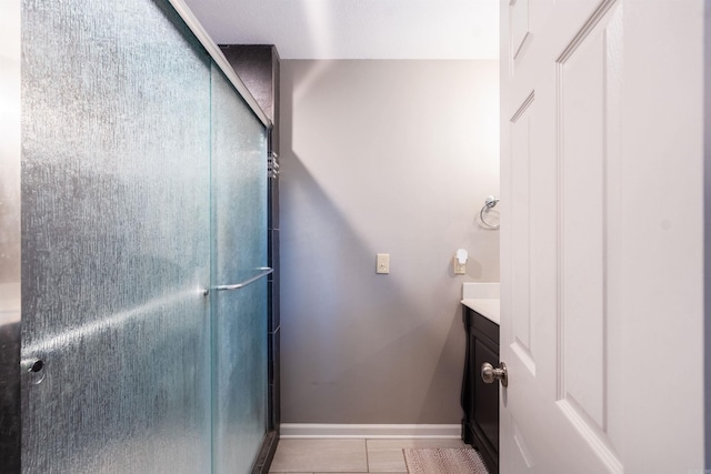 bathroom featuring tile patterned floors, a shower with shower door, and vanity