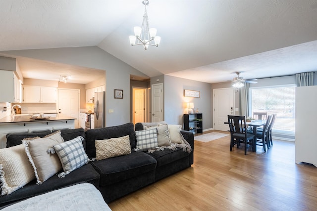 living room featuring lofted ceiling, sink, ceiling fan with notable chandelier, and light hardwood / wood-style floors