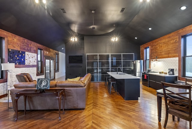 living room with sink, a fireplace, high vaulted ceiling, and light hardwood / wood-style flooring