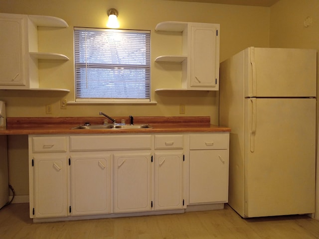 kitchen featuring white cabinetry, sink, wooden counters, and white refrigerator