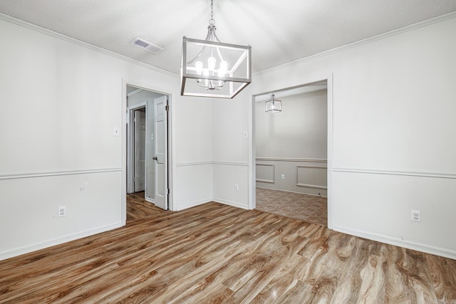 unfurnished dining area featuring hardwood / wood-style floors, a notable chandelier, ornamental molding, and a textured ceiling