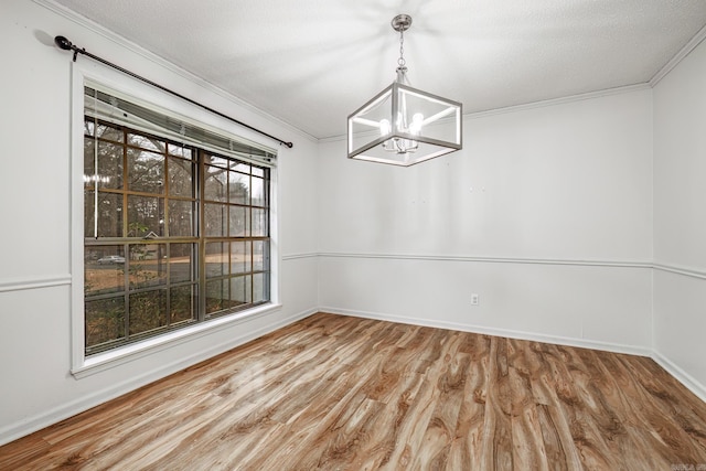 unfurnished dining area featuring hardwood / wood-style flooring, crown molding, a chandelier, and a textured ceiling