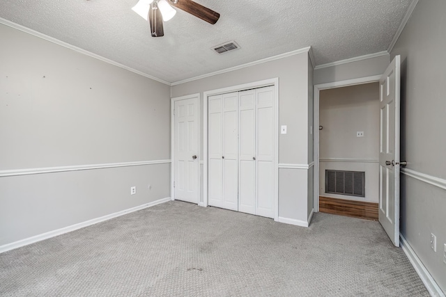 unfurnished bedroom with crown molding, light carpet, a textured ceiling, a closet, and ceiling fan