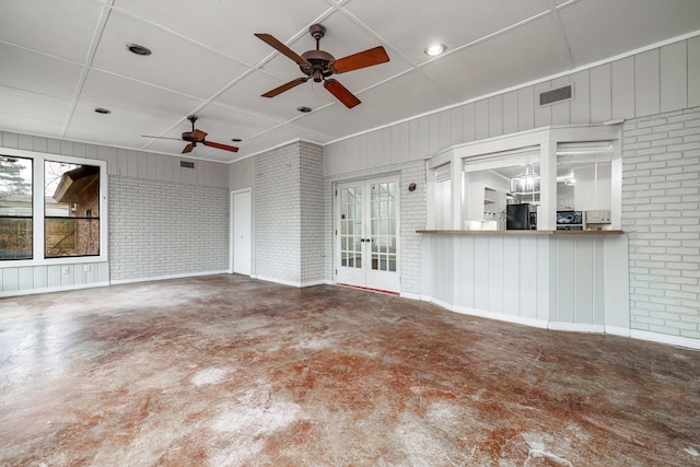 unfurnished living room featuring concrete floors, a healthy amount of sunlight, and brick wall