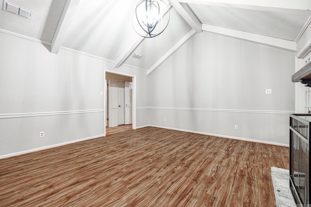 unfurnished living room featuring hardwood / wood-style flooring, vaulted ceiling with beams, a textured ceiling, and a chandelier