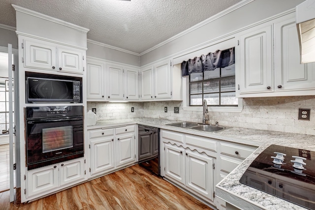 kitchen featuring white cabinets, sink, light hardwood / wood-style flooring, and black appliances