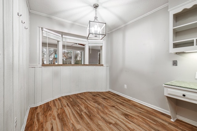 unfurnished dining area with crown molding, wood-type flooring, and a textured ceiling