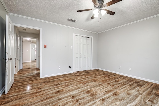 unfurnished bedroom featuring ornamental molding, a closet, a textured ceiling, and light wood-type flooring